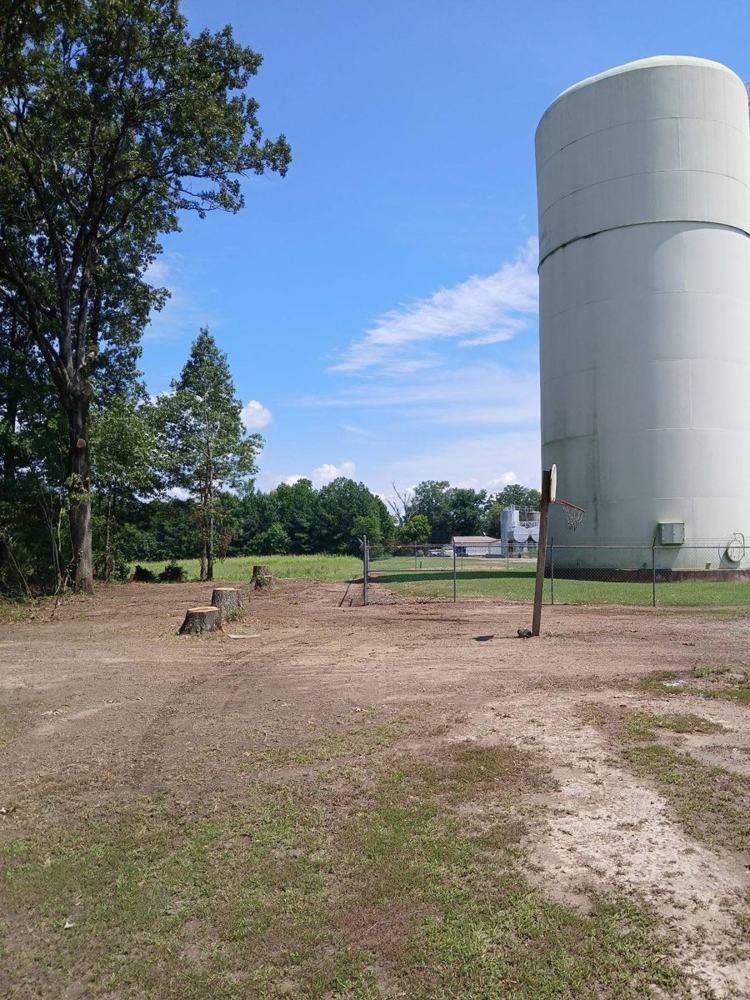 Open ground by a white water tower, cleared down to the dirt